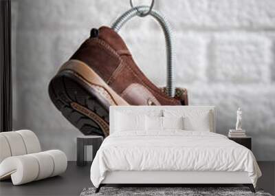 Comfortable brown suede shoes hanging on a white background wall Wall mural