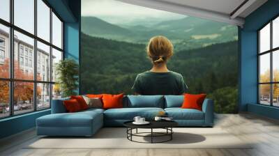 Child gazes at mountainous landscape under a cloudy sky in nature Wall mural