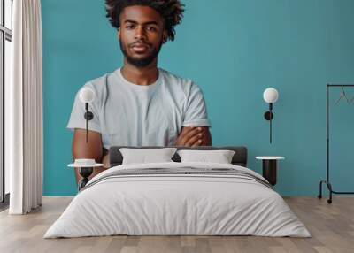 Confident Man With Afro Hairstyle Posing With Arms Crossed in a White T-Shirt Against a Blue Background Wall mural