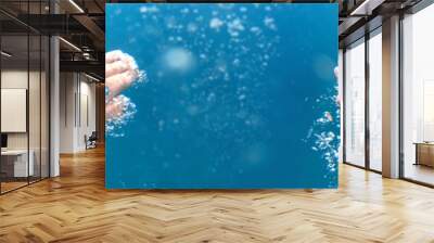 Underwater shoot of a diver swimming in a blue clear water, strong hands and lots of bubbles. Point of view shot Wall mural