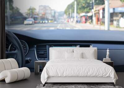 View from inside a car on a part of dashboard with a navigation unit and blurred street in front of a car Wall mural