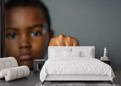 Portrait of a black boy with his fist extended to the camera on a light background. Generative AI. Wall mural