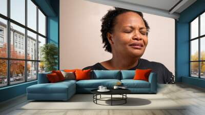 Black woman with eyes closed with sad expression on pastel background. Wall mural