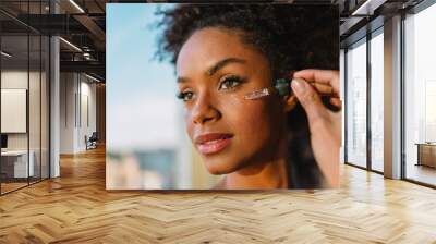 Close up portrait of Latina woman applying hyaluronic serum to her face. Wall mural