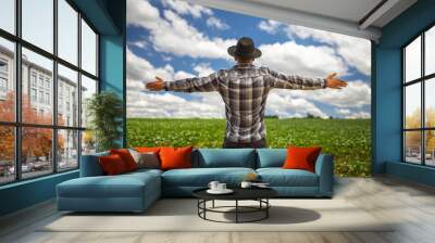 Happy young latin american farmer enjoying freedom with open hands on the farm and on sunset sky background. Wall mural