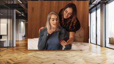 mother and adult daughter fiddling with cellphone in living room Wall mural