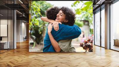 Two women hugging each other on a pleasant date in the park. Wall mural