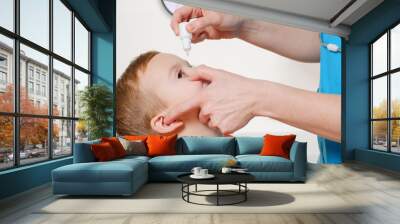 Closeup of doctor pouring eye drops in eye her patient. Wall mural