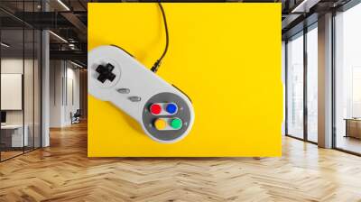 Photo of classic gray colored 8 bit game pad controller laying on yellow background. Wall mural