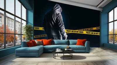 Photo of scary horror stranger stalker man in black hood and clothing on dark blue background with police lines. Wall mural