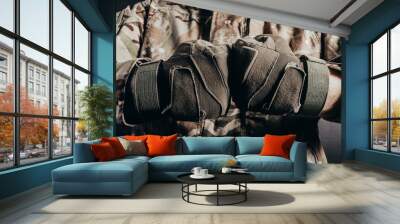 Photo of soldier in camouflaged uniform showing fist fight gesture in tactical gloves on black background. Wall mural