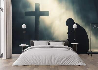 A person in devout prayer before a cross, with misty beams of light creating an ethereal atmosphere. This emotive image symbolizes faith, hope, and spirituality in moments of contemplation. Wall mural