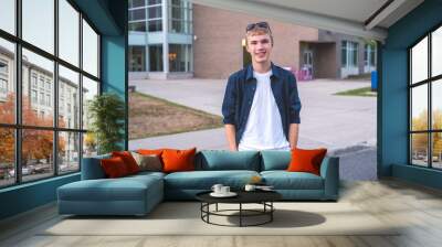 happy teenager standing outside of a school in a parking lot. Wall mural