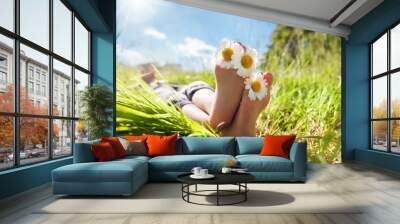 Child lying in meadow relaxing in summer sunshine Wall mural