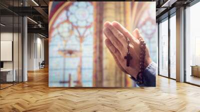 Hands folded in prayer in church with rosary beads and religious cross Wall mural