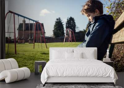 lonely child with depression sitting on play park playground bench Wall mural