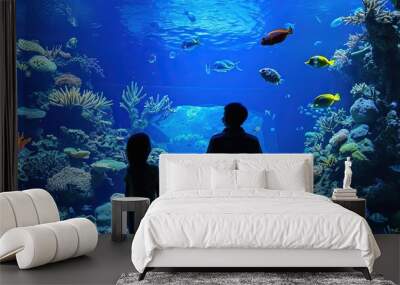 Silhouette of a family enjoying the aquarium - bright blue water filled with tropical fish and sea life Wall mural