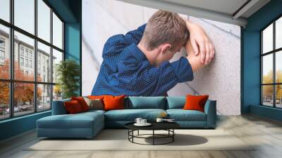 Teen crying into folded arms against a brick wall. Wall mural