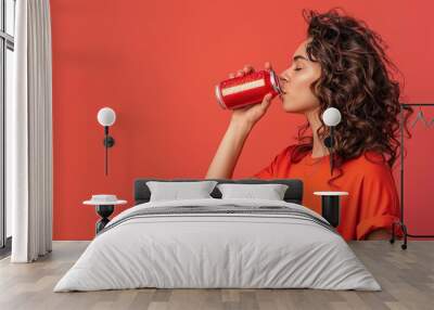 Woman drinking blank soda can on solid background with copy space. Red Wall mural