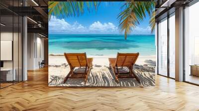 Idyllic tropical beach scene with two wooden lounge chairs, palm tree shade, white sand, and turquoise ocean under blue sky, vacation concept. Copy space. Wall mural