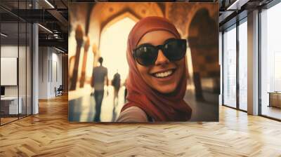 An attractive girl in a hijab and glasses takes a happy selfie Wall mural