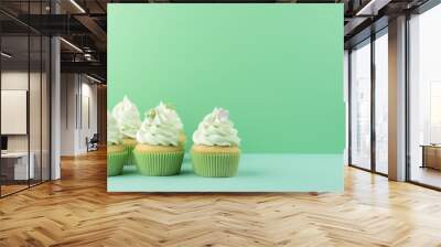 Green birthday cupcakes with copy space. Green cupcakes on green background Wall mural