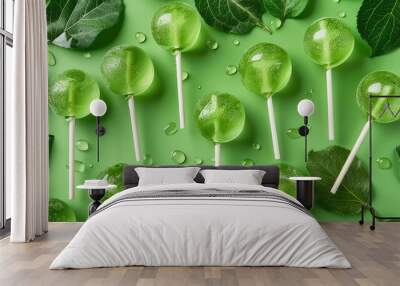 Green lollipops with apple flavor on a green background with apple leaves. Wall mural