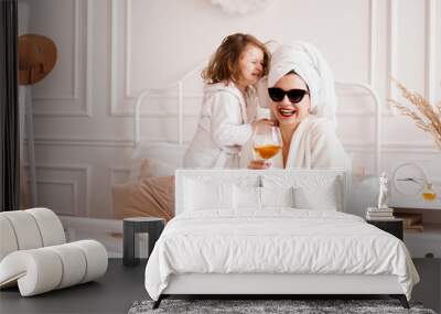 Mother and daughter in the bedroom in bathrobes. Happy daughter is jumping Wall mural