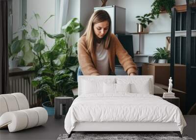 Woman packs things in a cardboard box in room. Moving to a new apartment Wall mural