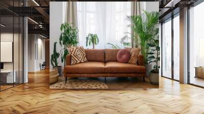 Brown sofa, potted green plants and wicker basket in room Wall mural