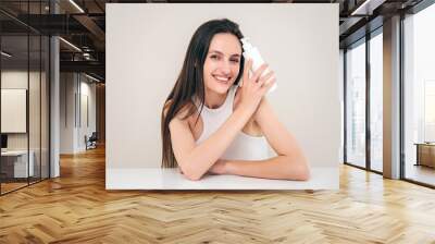 Happy woman with professional shampoo and conditioner in bottle looking at camera Wall mural