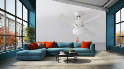 person turn on electric ceiling lamp with propeller indoors Wall mural