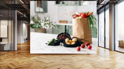 Various vegetables in paper grocery and black mesh bags on kitchen island Wall mural