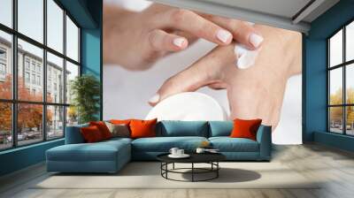 Woman applying soft hand cream on skin Wall mural