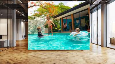 A  family enjoys playing in their private swimming pool while on vacation as they enjoy a short-term vacation rental property. Family lifestyle and leisure photo Wall mural