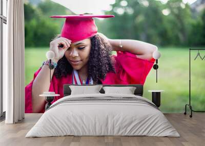 Candid Portrait of a beautiful multiethnic woman putting on her graduation cap and gown. Selective focus on her beautiful face Wall mural