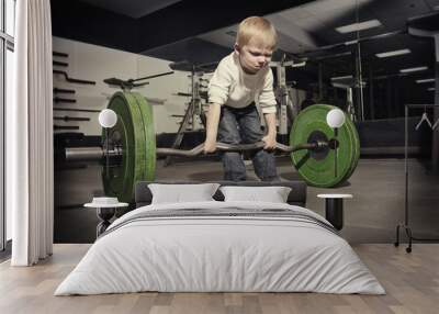 determined young boy trying to lift a heavy weight bar Wall mural