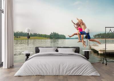 Group of kids jumping off the dock into the lake together during a fun summer vacation.  Wall mural