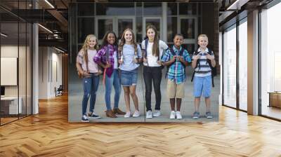 Large Group portrait of pre-adolescent school kids smiling in front of the school building. Back to school photo of a diverse group of children wearing backpacks and ready to go to school Wall mural