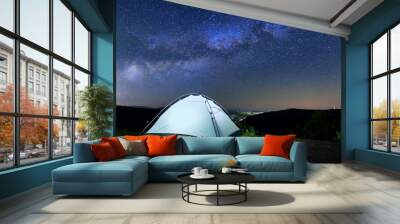 A tent glows under a night sky full of stars. Wall mural