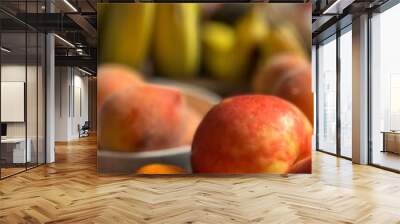 A vibrant close-up of assorted fresh fruits, featuring crisp apples and juicy oranges in the foreground, with ripe bananas softly blurred in the background, highlighting their vivid colors Wall mural