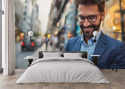 A man in a suit smiles while using a smartphone on a city street. Wall mural