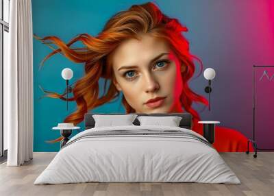 A young Caucasian woman with long, wavy red hair and green eyes,  against a blue background with red lighting Wall mural