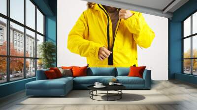 Serious bearded young man zipping up his bright yellow warm snowboarding anorak isolated on white Wall mural