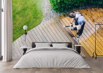 man cleaning terrace with a power washer - high water pressure cleaner on wooden terrace surface Wall mural