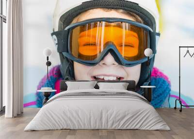 Ski, skier girl, winter vacation - happy child girl in goggles and protective helmet enjoining winter holidays Wall mural