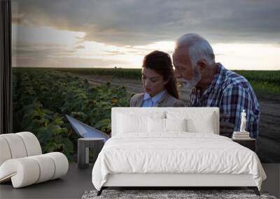 Business woman and peasant reading contract in field Wall mural