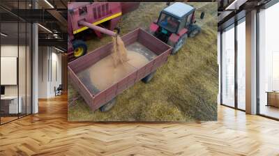 Combine harvester and tractor working in wheat field Wall mural