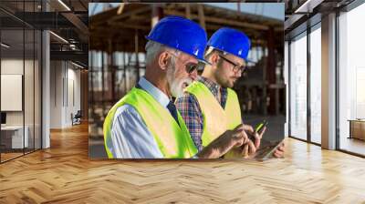 Engineers working on mobile at building site Wall mural