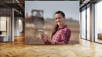 Farmer woman with tablet and tractor in field Wall mural